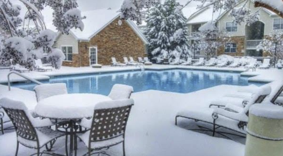 Pool deck and furniture covered in snow during the off-season